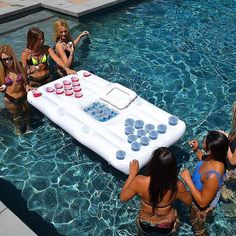 several women are in the pool with an inflatable beer game on its back