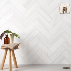 a potted plant sitting on top of a wooden stool in front of a white tiled wall