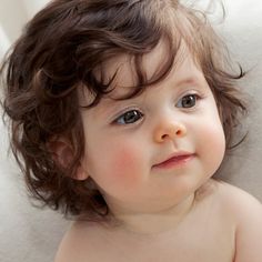 a close up of a baby with curly hair