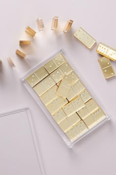 several pieces of gold are arranged on a white surface next to small wooden dows