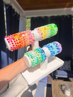 three colorful toothbrushes are being held by a person's hand in front of a window