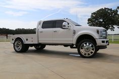 a large white truck parked in a parking lot next to a horse pen and fence