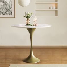 a white table with flowers and candles on it in front of a wall mounted art piece