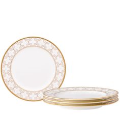 four white and gold dinner plates, one with an intricate design on the rims