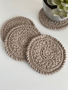 three crocheted coasters on a table next to a potted succulent