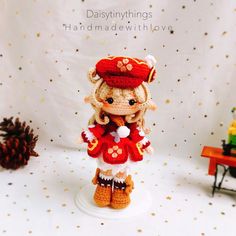 a crocheted doll is standing on a white surface with pine cones in the background