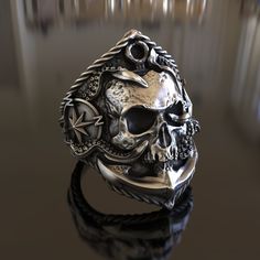 a silver ring with a skull and compass on it