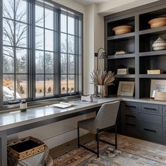 a home office with large windows and built - in bookshelves