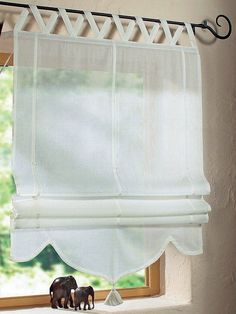 an elephant figurine sitting on top of a window sill in front of a curtain