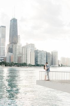 a man and woman standing next to each other near the water