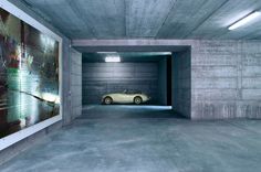 a car is parked in the middle of an empty parking garage with paintings on the walls