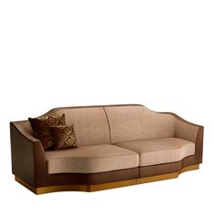 a brown and tan couch with two pillows on top of it's armrests