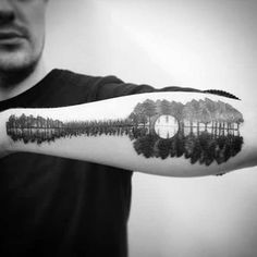 a person with a tattoo on their arm that has trees and a clock in the middle