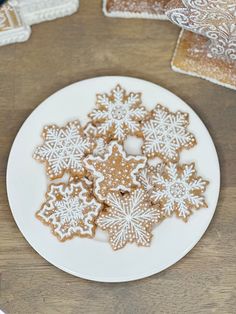 a white plate topped with snowflake cookies on top of a wooden table next to other plates