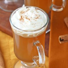 two mugs filled with hot chocolate and whipped cream on top of a wooden table