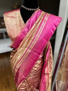 Indulge in ethereal elegance with our exquisite Kora Tissue Silk Saree, featuring a luxurious Katan Silk border adorned with shimmering gold zari. This masterpiece combines the delicate transparency of Kora tissue with the rich texture of Katan silk, creating a captivating contrast. The saree's ethereal beauty is further enhanced by the intricate gold zari work on the border, adding a touch of opulence. Perfect for weddings, cocktail parties, or any special occasion where you desire to make a lasting impression, this saree is a must-have for the discerning woman. Fabric: Kora by Tissue Silk Saree with Katan Silk Border Color: Rose Gold Embellishments: Gold Zari Occasion: Weddings, Parties, Festive Photos don't do justice .. this saree is just... glamorous Comes with fall/ Pico / tassels an Elegant Pink Handloom Pre-draped Saree, Elegant Pink Pre-draped Saree In Tussar Silk, Elegant Chanderi Pre-draped Saree For Celebration, Elegant Gold Pre-draped Saree For Festivals, Gold Raw Silk Pre-draped Saree With Zari Work, Gold Pre-draped Raw Silk Saree With Zari Work, Gold Raw Silk Pre-draped Saree For Festivals, Gold Dupatta For Party In Transitional Season, Gold Dupatta For Transitional Party Season