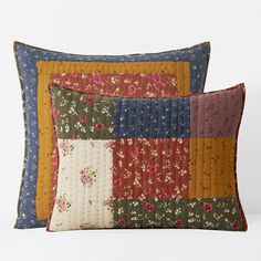 two decorative pillows with different colored patchwork designs on them, one has a flowered design and the other has a floral pattern