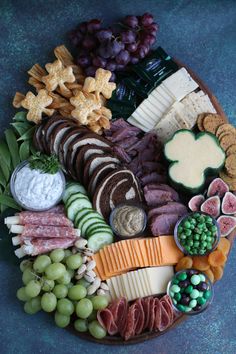 a platter filled with cheese, crackers, grapes and meats is shown