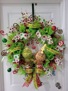 a christmas wreath with green and red decorations on the front door is decorated with an elf's head