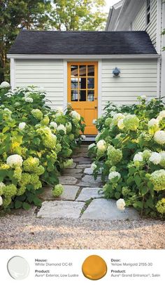 a yellow door sits in the center of a garden with hydrangeas around it