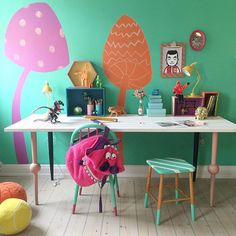 a room with green walls and colorful decorations on the wall, including a white table