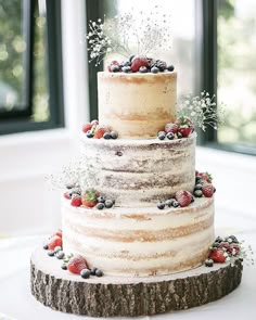 the wedding cake is decorated with berries and greenery