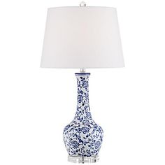 a blue and white vase lamp with a white shade on it's side table