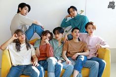 the group of young people are posing for a photo on the yellow couch in front of the white wall