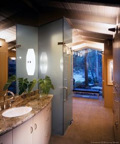 a bathroom with two sinks and a walk in shower next to a large glass door