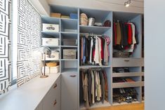 an organized closet with clothes, shoes and other items on shelves next to a window