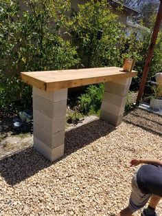 a person kneeling down in front of a bench made out of cinder blocks and wood