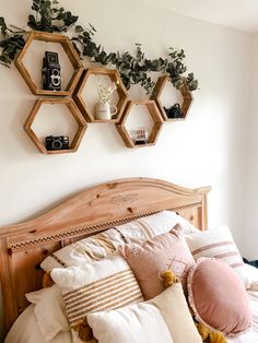 a bed topped with lots of pillows next to two hanging hexagonals on the wall