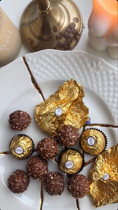 some chocolates are on a white plate with gold foil