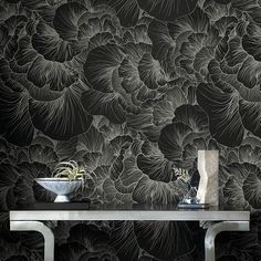 an artistic wallpaper design with black and white flowers on the side table in front of it