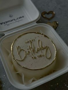 a birthday cake in a plastic container with the words happy birthday written on it and gold foil