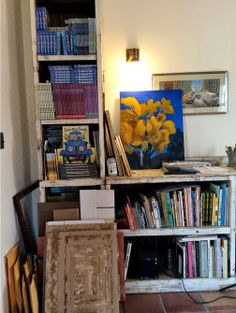 a bookshelf filled with lots of books next to a painting