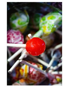 a red lollipop sitting on top of a pile of candies next to each other