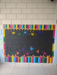 a blackboard with colorful crayons on it in front of a brick wall