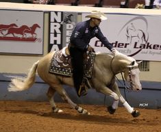 a man riding on the back of a white horse in an arena at a rodeo