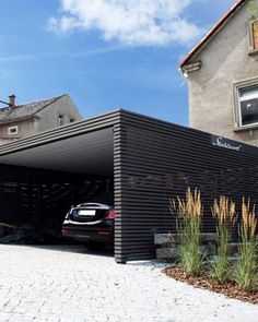 a black car is parked in front of a house with an awning over it