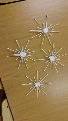 four white sticks are arranged in the shape of snowflakes on a wooden table