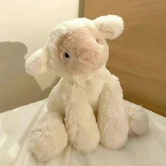 a white stuffed animal sitting on top of a bed