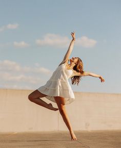 a woman in a white dress is doing a trick