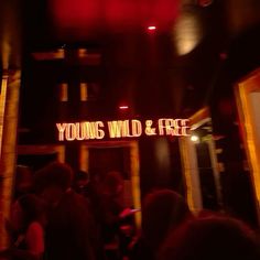 the youngs wild and free sign is lit up at night with people standing outside