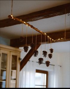 some pine cones hanging from a beam in a room with wood beams and lights on the ceiling