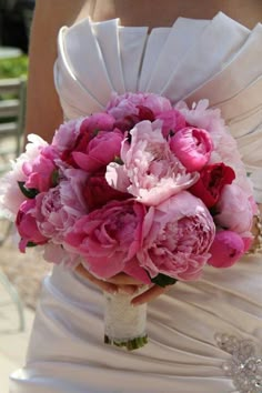 a bride holding a bouquet of pink peonies