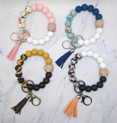 three different bracelets with tassels and beads on them sitting on a marble surface