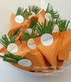 orange and white paper flowers in a bowl with name tags on the top for each flower