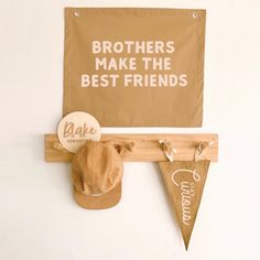 a brown hat is hanging on the wall next to a sign that says brothers make the best friends