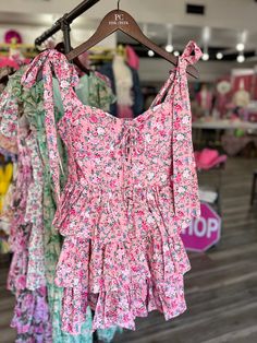 Flaunt your style in the Pierce Floral Corset Ruffle Mini Dress. This charming dress features adjustable shoulder straps that tie into a playful bow, a flattering corset detail, and cascading ruffles. The elastic ruching back ensures a perfect fit. Perfect for a fun and flirty look! (Bow-tiful style - No wonder it's tied up in a bow!) Pink Tiered Dress With Adjustable Straps, Pink Dress With Ruffled Tie Straps, Ruffled Tie Straps Mini Dress For Garden Party, Garden Party Mini Dress With Ruffled Tie Straps, Spring Mini Dress With Bow Straps For Brunch, Pink Ruffle Dress With Ruffled Straps For Brunch, Pink Mini Dress With Tie Back And Ruffled Straps, Spring Ruffle Dress With Ruffled Straps And Hem, Spring Ruffle Dress With Ruffled Straps For Day Out